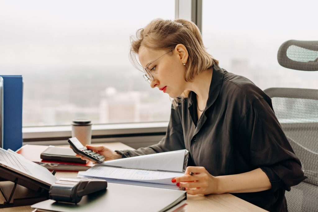 Woman accountant calculating financial documents at office desk.